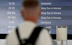 Passengers look at an electronic board displaying cancelled flights at the Ngurah Rai International Airport in Tuban near Denpasar on Indonesia's resort island of Bali on March 21, 2025, after Mount Lewotobi Laki-Laki volcano in the archipelago nation's east erupted, shooting dark ash eight kilometres into the sky. (Photo by SONNY TUMBELAKA / AFP)