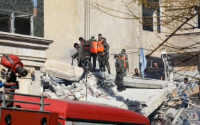Security and emergency personnel search the rubble of a building destroyed in a reported Israeli strike in Damascus on January 20, 2024. An Israeli strike on Damascus killed the Iranian Revolutionary Guards' intelligence chief for Syria and three other Guards members on January 20, Iran said, in an attack that tore into a multi-storey residential building. (Photo by Louai BESHARA / AFP)