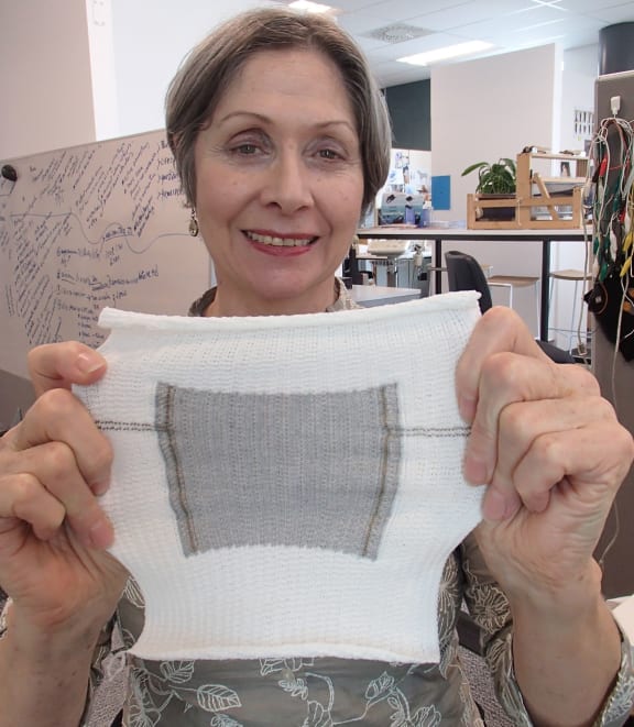 Frances holding a square of knitted fabric with a silver knitted centre