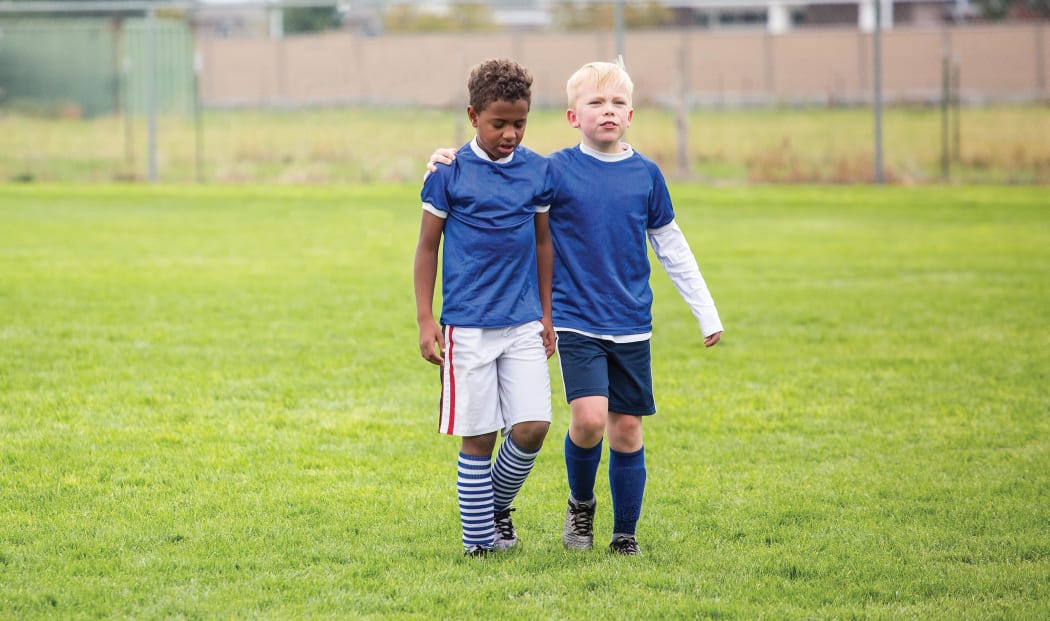 Two boys, one black, one white playing sport together,