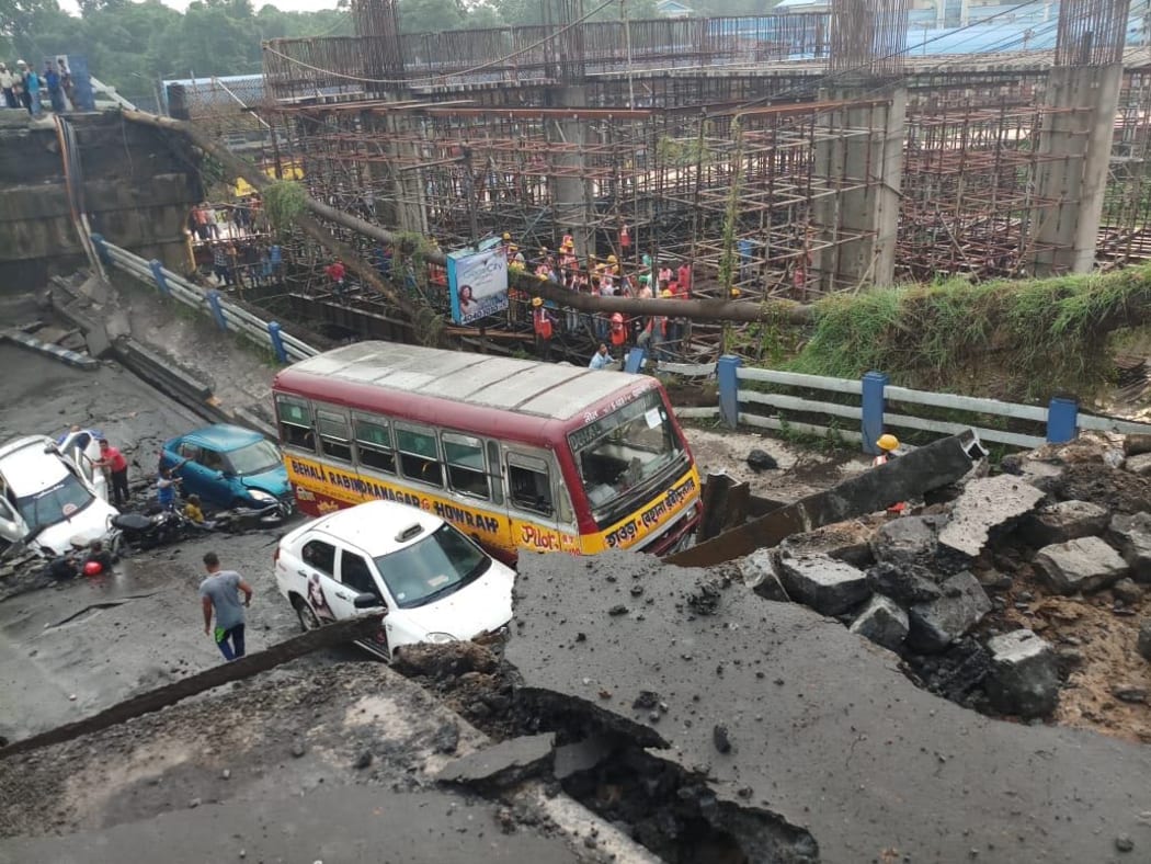 Indian rescue teams and onlookers stand on rubble and atop Majerhat bridge after a segment of the bridge suddenty collapsed in Kolkata in the Indian state of West Bengal.