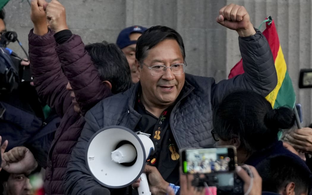 Bolivian President Luis Arce raises a clenched fist surrounded by supporters and media, outside the government palace in La Paz, Bolivia, on 26 June, 2024.