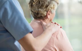 Nurse putting hand on elderly woman's shoulder