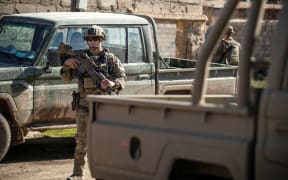 A US soldier stands near military vehicles as a convoy patrols an area in the town of Tal Hamis, southeast of the city of Qameshli in Syria's northeastern Hasakeh governorate, on January 24, 2024. (Photo by Delil SOULEIMAN / AFP)