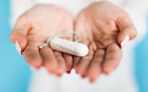 Woman holding a tampon, blue background