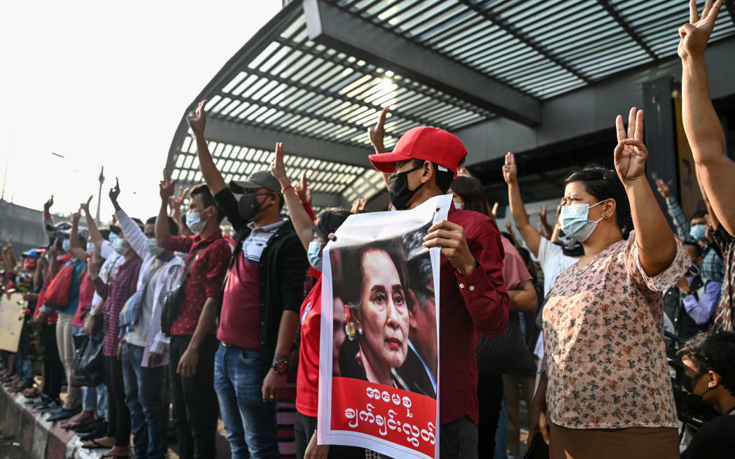 Protesters hold up the three finger salute and placards during a demonstration against the military coup in Yangon on February 7, 2021. (Photo by YE AUNG THU / AFP)