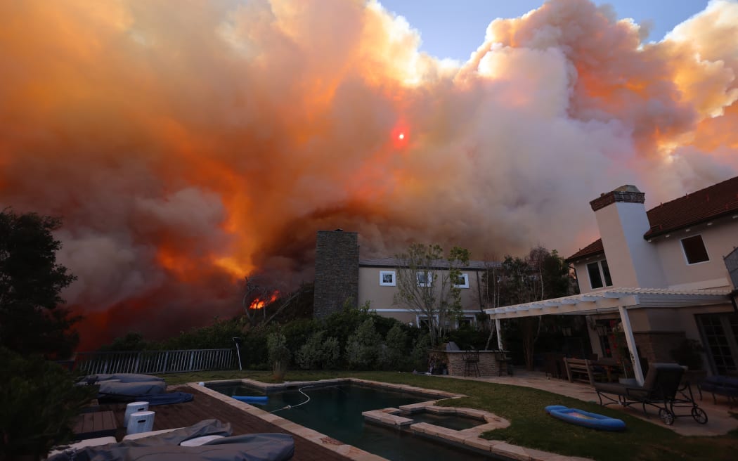A brush fire burns near homes in Pacific Palisafes, California on January 7, 2025. - A fast-moving brushfire in a Los Angeles suburb burned buildings and sparked evacuations Tuesday as "life threatening" winds whipped the region. More than 200 acres (80 hectares) was burning in Pacific Palisades, a upscale spot with multi-million dollar homes in the Santa Monica Mountains, shuttering a key highway and blanketing the area with thick smoke. (Photo by David Swanson / AFP)