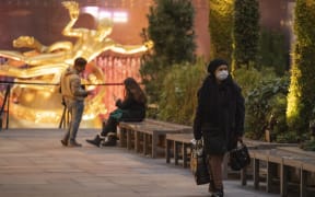 A woman wearing a face mask walks along Rockefeller Center Plaza on Friday, March 2020 in New York, NY.