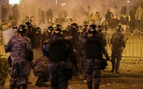 Lebanese riot police clash with anti-government demonstrators (background) in Beirut.