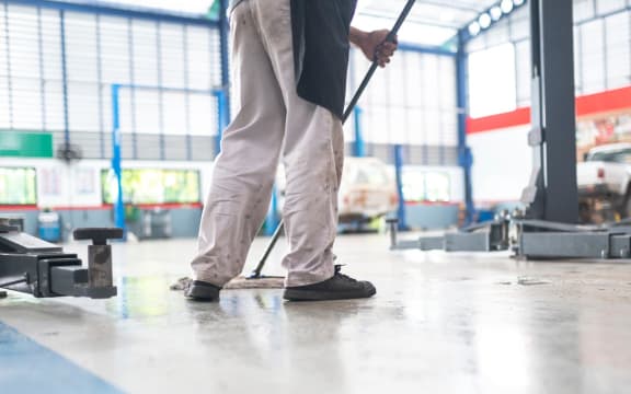mechanic in auto repair center Cleaning using a mop Squeeze water from the epoxy floor. in the car repair service center