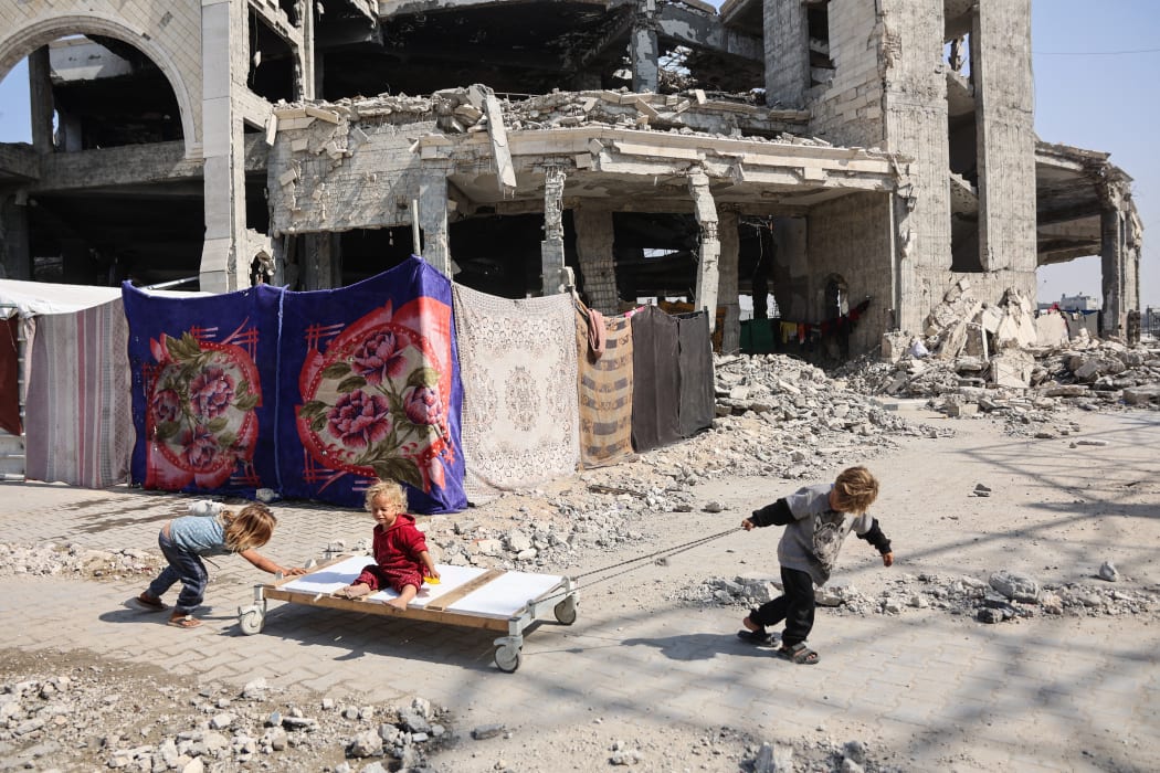 Displaced Palestinian children play outside the damaged Imam al Shafi’i Mosque, where their families have taken shelter, in the Zeitoun neighbourhood of Gaza City on October 23, 2025. (Photo by Omar AL-QATTAA / AFP)