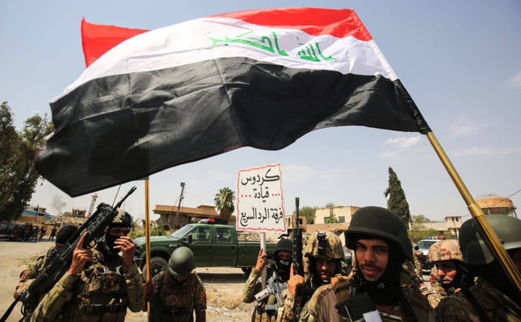 Members of the Iraqi federal police wave national flags during a parade in the Old City of Mosul on 2 July 2017.