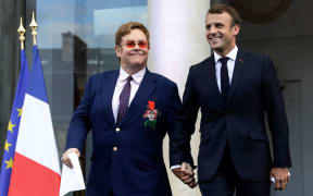 French President Emmanuel Macron (R) and British singer-songwriter Elton John arrive to speak to a crowd in the courtyard of the Elysee Palace in Paris, on June 21, 2019,