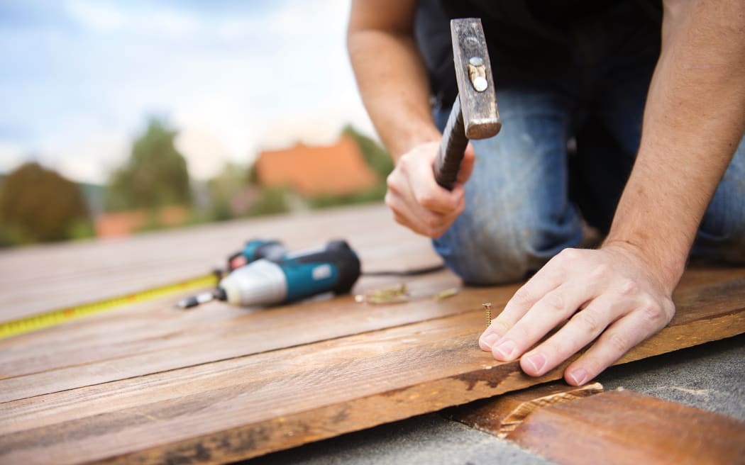 A worker hammers down timber for a house's deck.