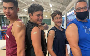 From left, Te Kahui, Te Haeata and Mahara Kururangi with their father Tumanako Kururangi showing off the plasters on their arms after they were vaccinated at Te Poho o Rawiri Marae.