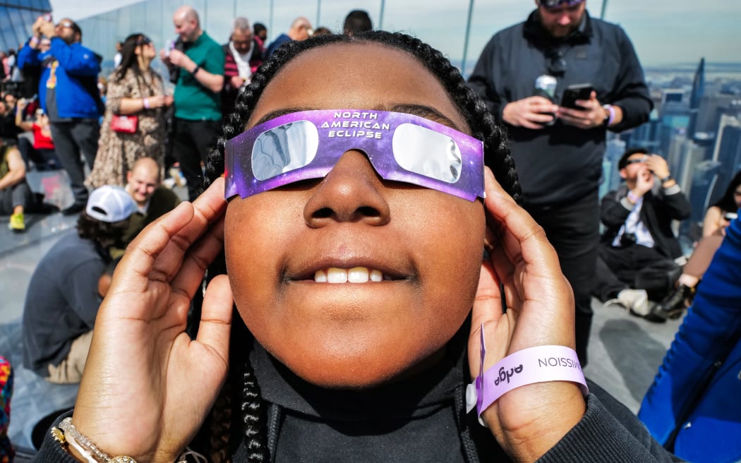 A young girl looks toward the sky at the 'Edge at Hudson Yards' observation deck during a solar eclipse in New York City on April 8, 2024.