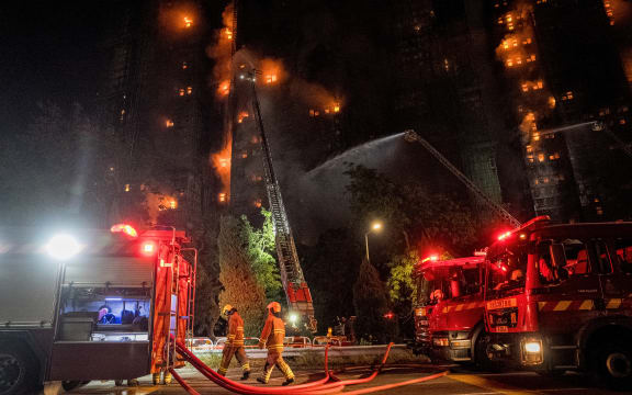 Firefighters spray water on flames as a major fire engulfs several apartment blocks at the Wang Fuk Court residential estate in Hong Kong's Tai Po district on November 26, 2025. A huge fire ripped through several high-rise blocks in a Hong Kong residential estate on November 26, killing at least 13 people, with media reporting that some residents were trapped inside. (Photo by AFP)