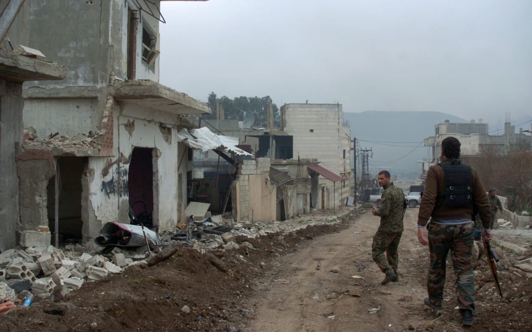 Syrian forces patrol a street in the town of Zara during fighting against rebels.