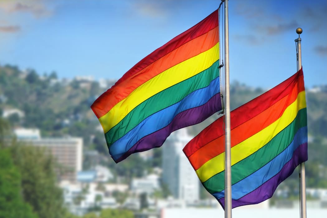 21543261 - a pair of rainbow flags waving in wind against city background of west hollywood, california