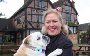 Christchurch born landlady, Vanda Perry stands in fron of the Crown Inn that she runs in the village of Capel in Surry holding her English bulldog. Gladys