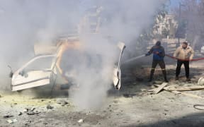 A firefighter and a civilian extinguish fire from a car following an Israeli strike in the southern Lebanese village of Khiam on January 3, 2026.