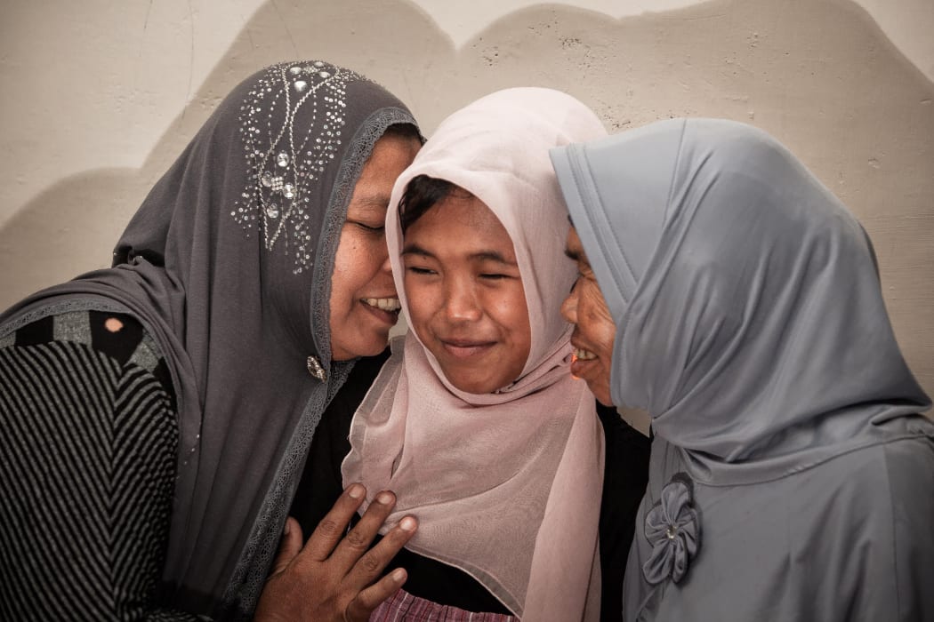 Indonesian mother Jamaliah (left) hugs her daughter Raudhatul Jannah (centre) after they were reunited in Meulaboh, Aceh, Indonesia on August 7, 2014. The girl went missing during the Indonesian tsunami 10 years ago.