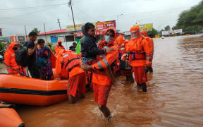 Rescuers, shown here in Kolhapur,  have been using boats to ferry people to safety, but have been hampered by downpours.