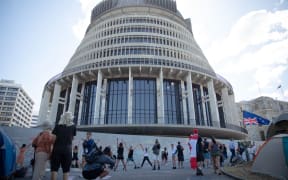 Anti-vaccine, anti-mandate protest in Wellington on Parliament grounds on 16 February 2022.
People doing yoga, stretching on the forecourt. Chalk art on the walls.