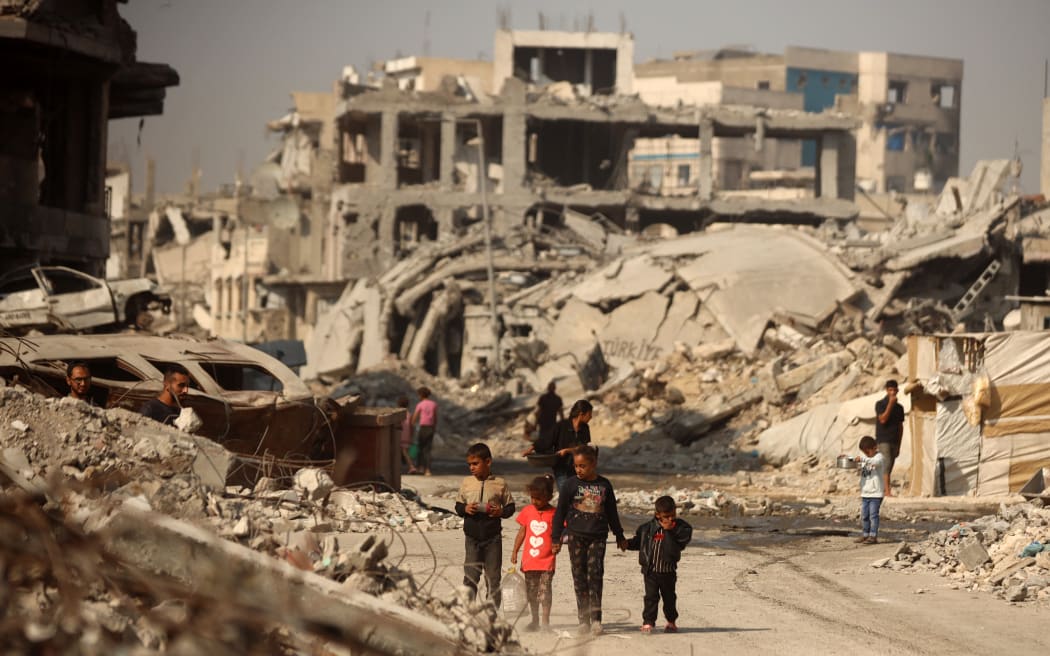 Palestinians walk amid the rubble of destroyed buildings in Gaza City, Palestine, on 5 November, 2025, during a ceasefire in the two-year-long Israel-Hamas war.