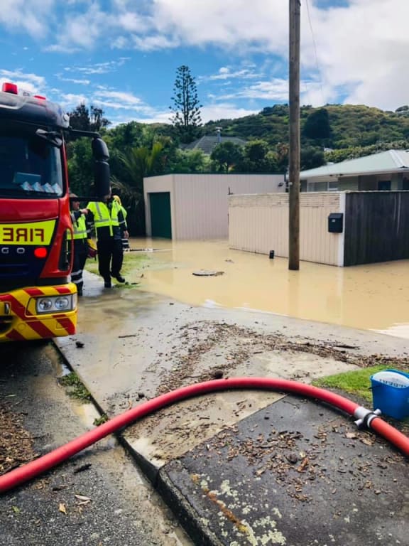 Fire fighters trying to pump water from a Plimmerton home.