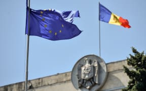 The EU flag waves close to the Moldovan Parliament building.
