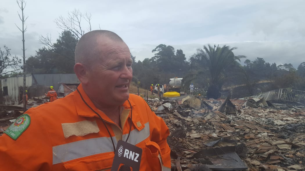 Principal rural fire officer Paul Shaw with the charred remains of one of the houses destroyed by the fire.