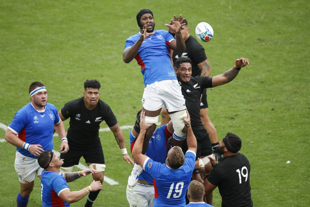 Namibia's lock Tjiuee Uanivi (C) jumps for the ball in a line out  during the match between New Zealand and Namibia.
