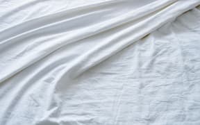 Top view of wrinkles on an unmade bed sheet after waking up in the morning.
