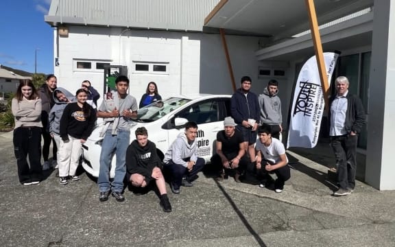 Young people by and around a charity car with signage on the door of charity Youth Inspire