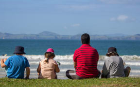 Father and Three Children Sitting at Matauri Bay Beach Northland New Zealand Watching the Waves