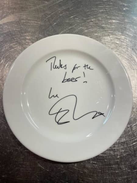 Ed Sheeran's signature on a white plate from Wellington's Monsoon Poon Bar, with the message "Thanks for the beer!"