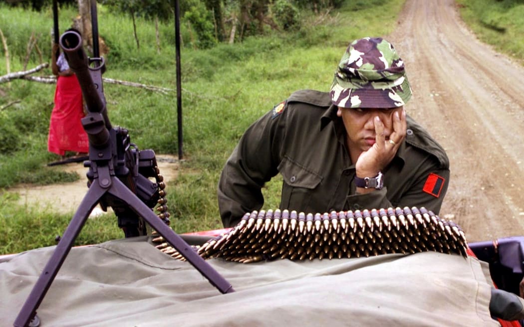 A soldier guards the road to Nasova village after a soldier and a policeman were killed in an ambush by the last rebel supporters of coup leader George Speight in Fiji 2000.
