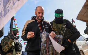 Hamas militants escort Israeli hostage Iair Horn on a stage before handing him over to a Red Cross team in Khan Yunis, in the Gaza Strip, on Saturday 15 February.