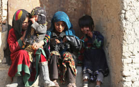 Children sit at the doorstep of a house along the street in Kabul on 28 December, 2022.
