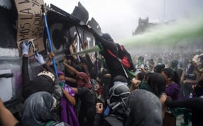 Women try to pull down a security fence during a demonstration to commemorate the International Women's Day in Mexico City.