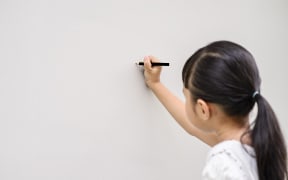 Asian girl writing on wall