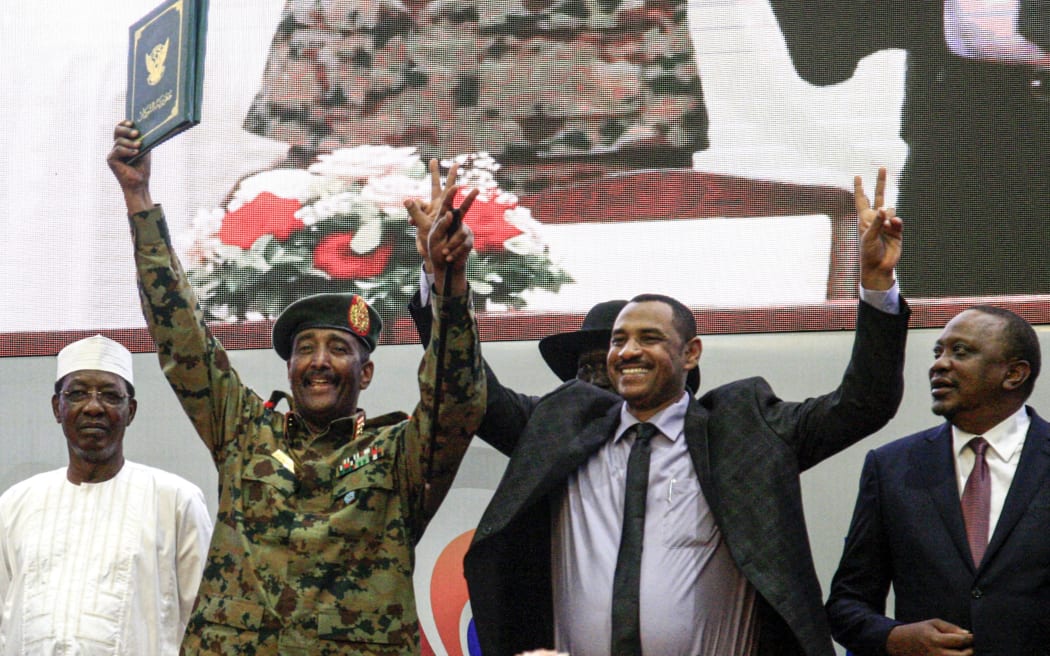 Sudan's protest leader Ahmad Rabie (C-R),  and  General Abdel Fattah al-Burhan (C-L), the chief of Sudan's ruling Transitional Military Council (TMC), during a ceremony , in the capital Khartoum on August 17, 2019,