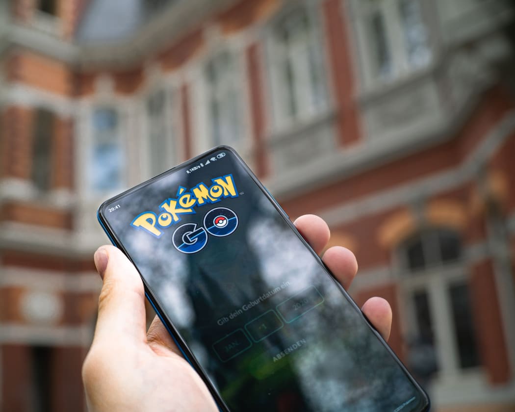 A person holding a phone playing Pokemon Go in a street.