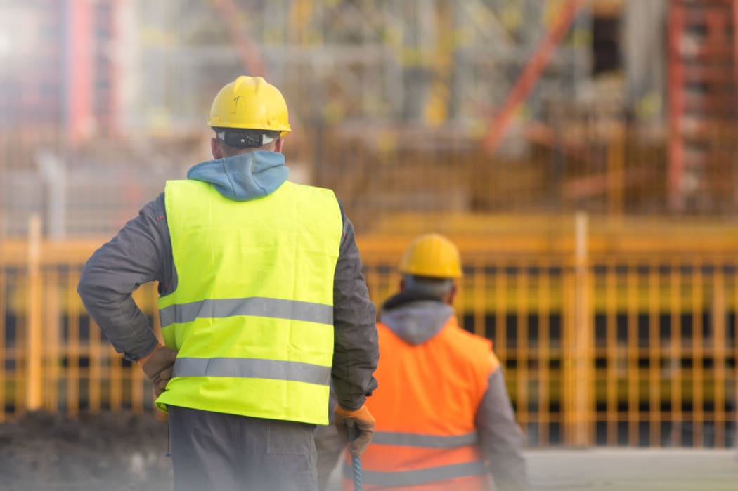 Two builders in yellow and orange at the construction site