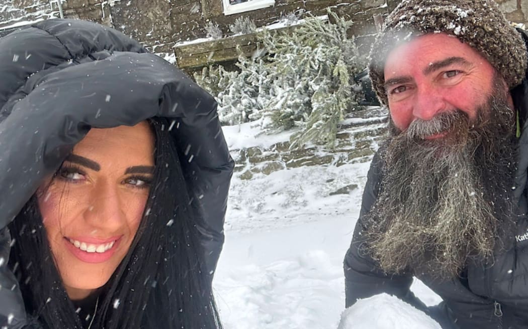 Nicole and Paul smile. They are standing outside in heavy snow, wearing big jackets. They hold snowballs in their hands.