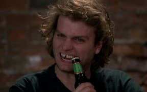 Mac DeMarco opening a beer with his teeth