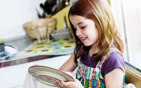A photo of a very cute girl wiping the dishes in the kitchen