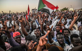Sudanese protesters gather as they shout slogans and wawe national flags during a protest outside the army headquarters in the capital Khartoum on April 21, 2019.