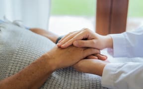 Doctors or nurses hold hands of elderly patients to support and soothe.